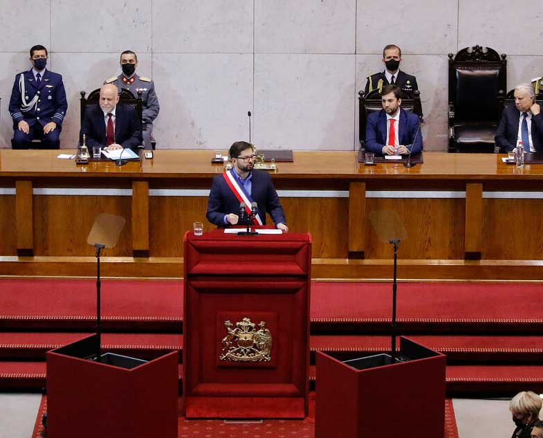 Foto dentro del congreso nacional donde aparece el presidente gabriel boric hablando sobre un estrado vestido de terno y con la banda presidencial.