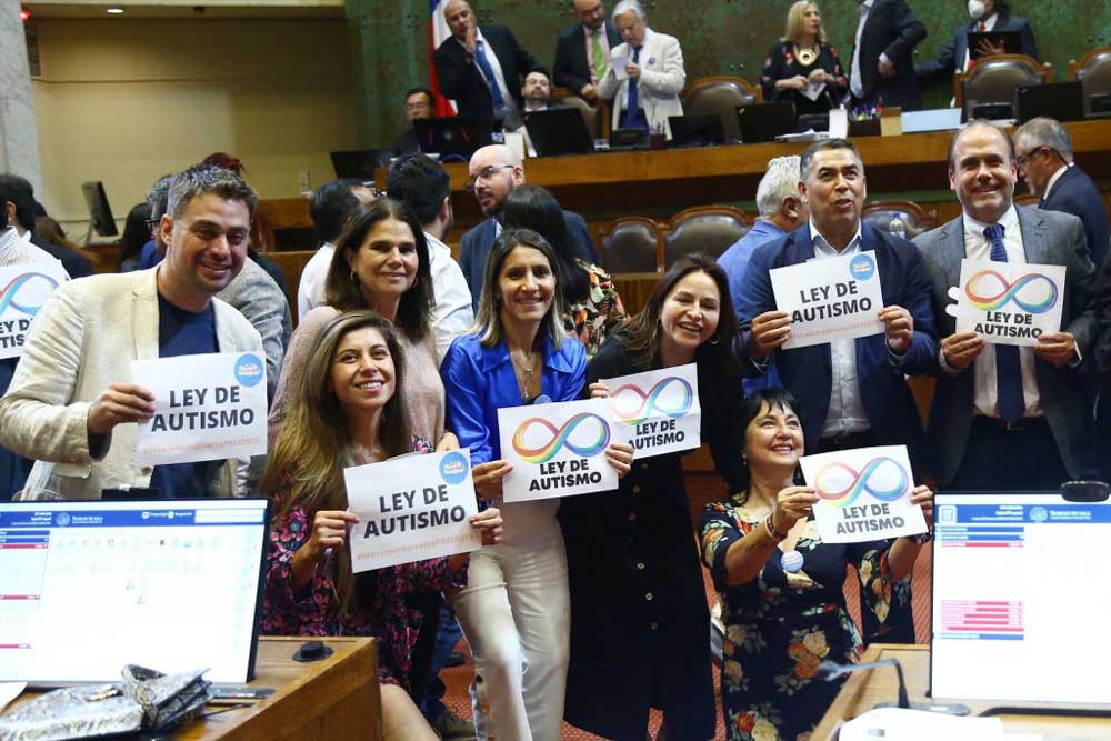 Foto dentro de la cámara de diputados donde aparece un grupo de diputados y diputadas sosteniendo carteles que dicen ley de autismo