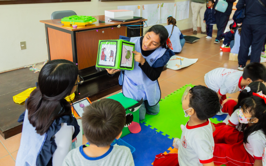 Foto dentro de una sala de clases en una escuela especial donde la profesora le muestra pictogramas a sus alumnos.