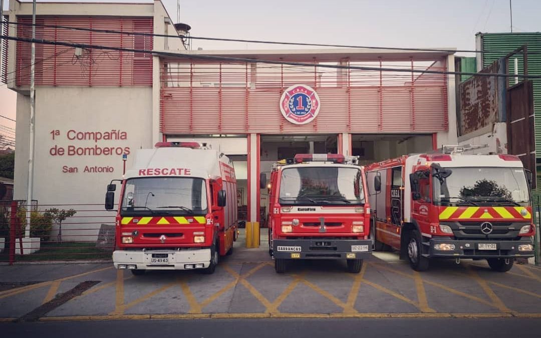 Foto de la 1era compañía de bomberos de san antonio donde hay 3 carros de bomberos grandes estacionados en la entrada.